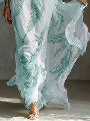 Lower view of the mint feather-print maxi dress showing the flowing skirt and ruffled edge.