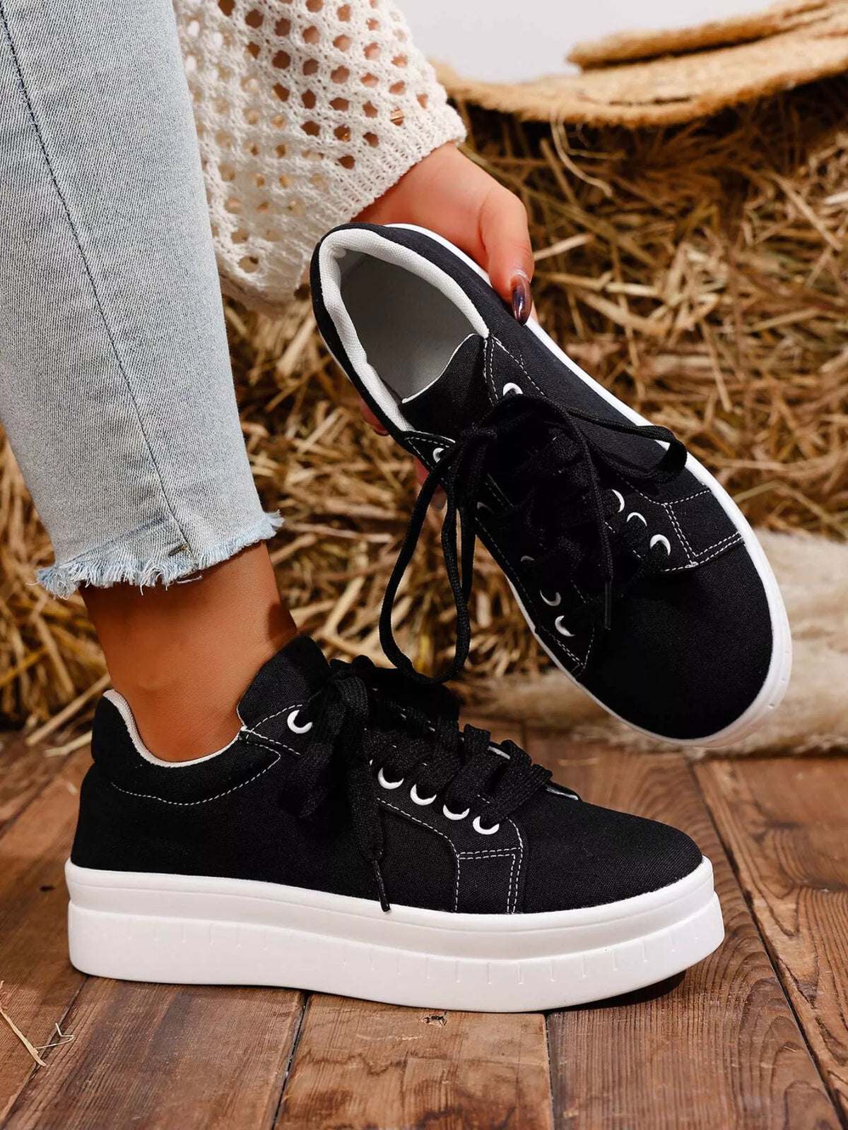 Black lace-up platform sneaker held to show outsole