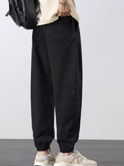 Side-back view of black joggers with a rear patch pocket and elastic ankle cuffs.