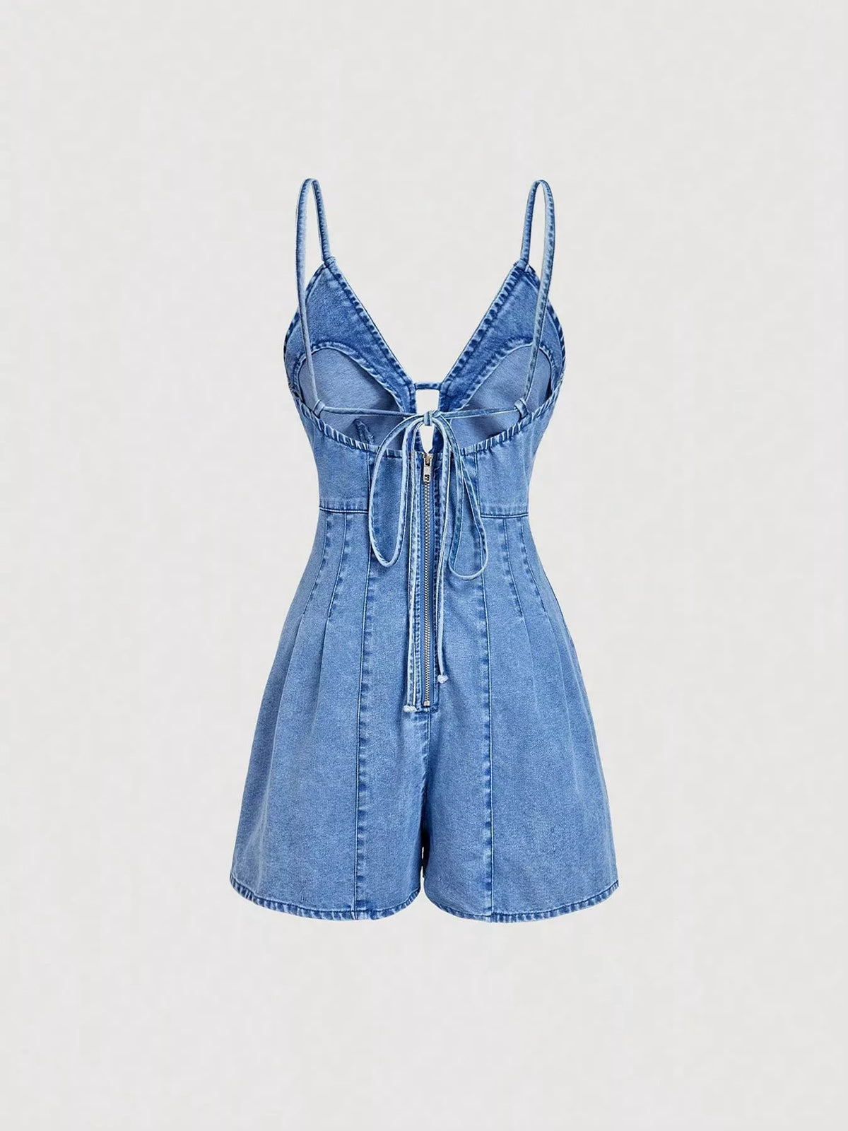 Back view of the light-wash denim romper showing narrow straps and a tie across the open back.