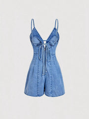 Back view of the light-wash denim romper showing narrow straps and a tie across the open back.