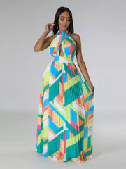 Front view of a turquoise geometric halter dress with the pleated skirt held out at both sides.