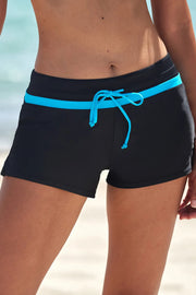 Front view of black swim shorts with a bright turquoise waistband stripe and matching drawstring, modeled.