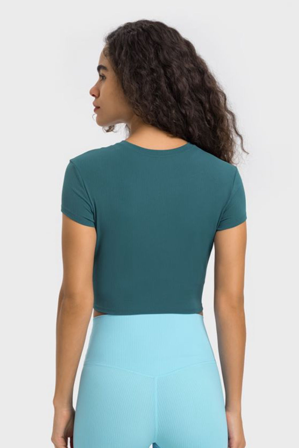 Back view of deep teal cropped T-shirt with light blue leggings