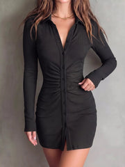 Front view of black long-sleeve ruched mini dress with collared V-neck and button front.
