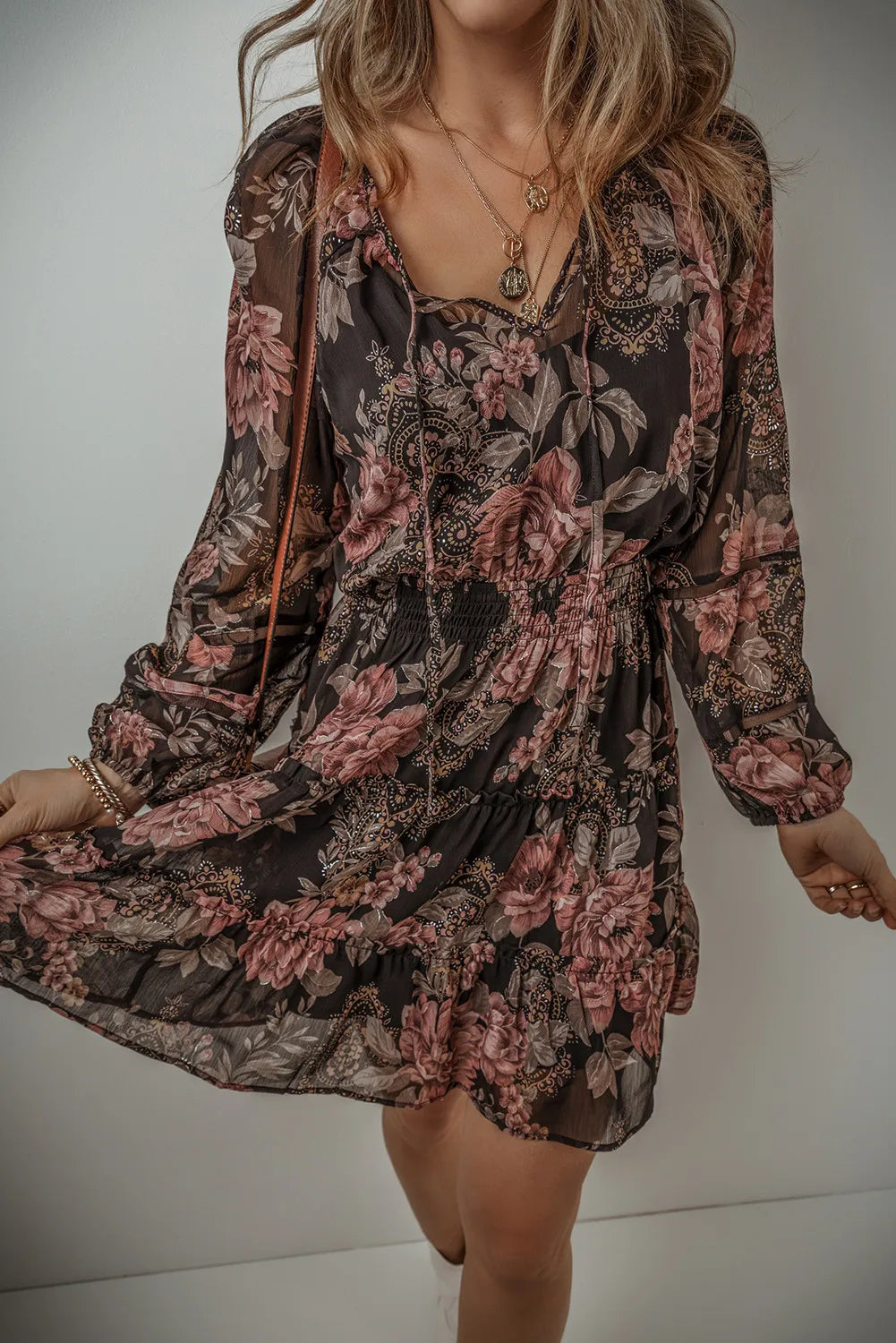 Model showing the dark floral dress gathered at the waist and flared skirt