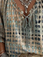 Close view of the beige spotted blouse neckline, ruffle trim and tied front neckline