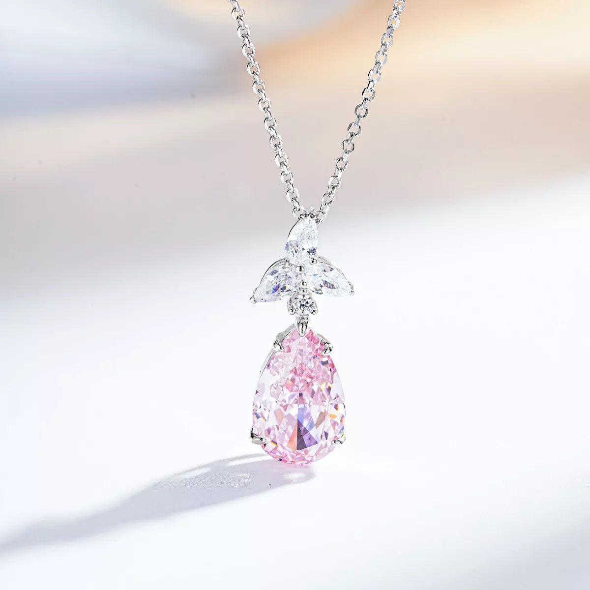 Blush-pink teardrop zircon pendant with a clear-stone accent on a silver-tone chain