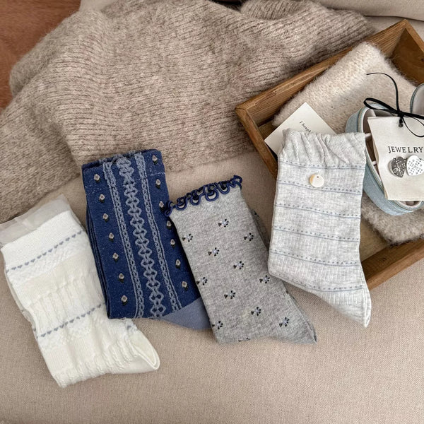 Assorted blue, gray and white knit socks arranged on a blanket