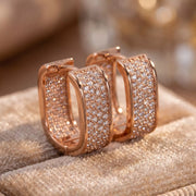 Rose-gold-tone square hoop earrings with clear stones on pale fabric