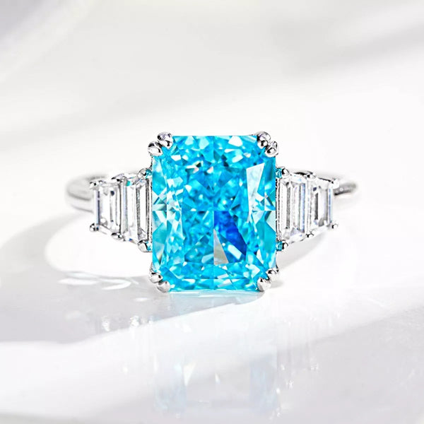 Pastel blue rectangular zircon ring with clear baguette side stones on a white background