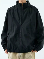 Model wearing black zip-up raglan jacket with stand collar, zipped front view