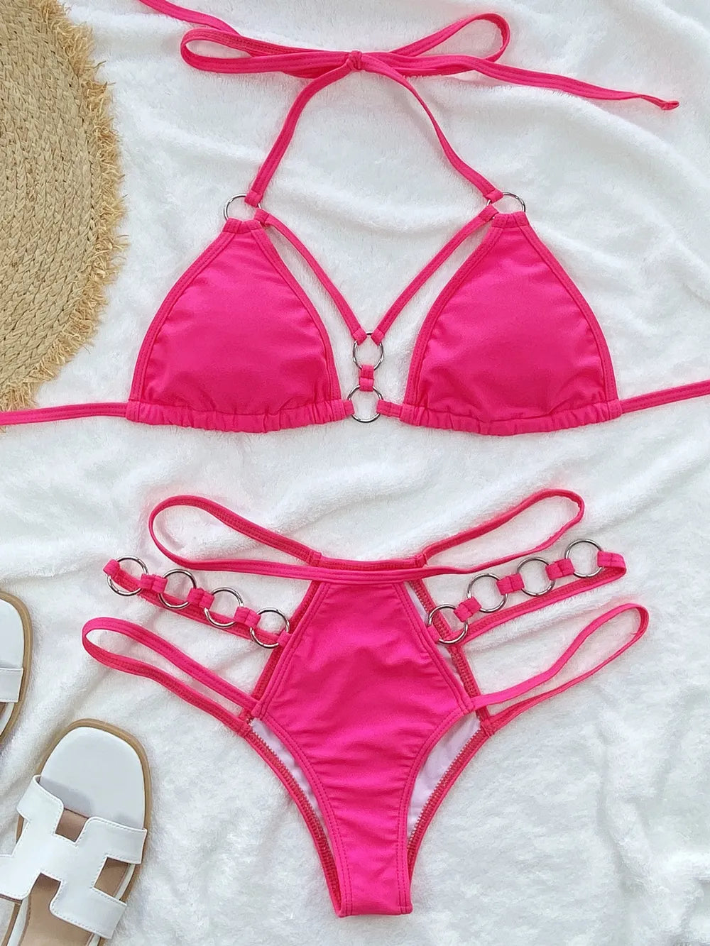 Bright pink cutout halter bikini set arranged flat with matching ring-detail bottoms