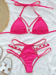 Bright pink cutout halter bikini set arranged flat with matching ring-detail bottoms