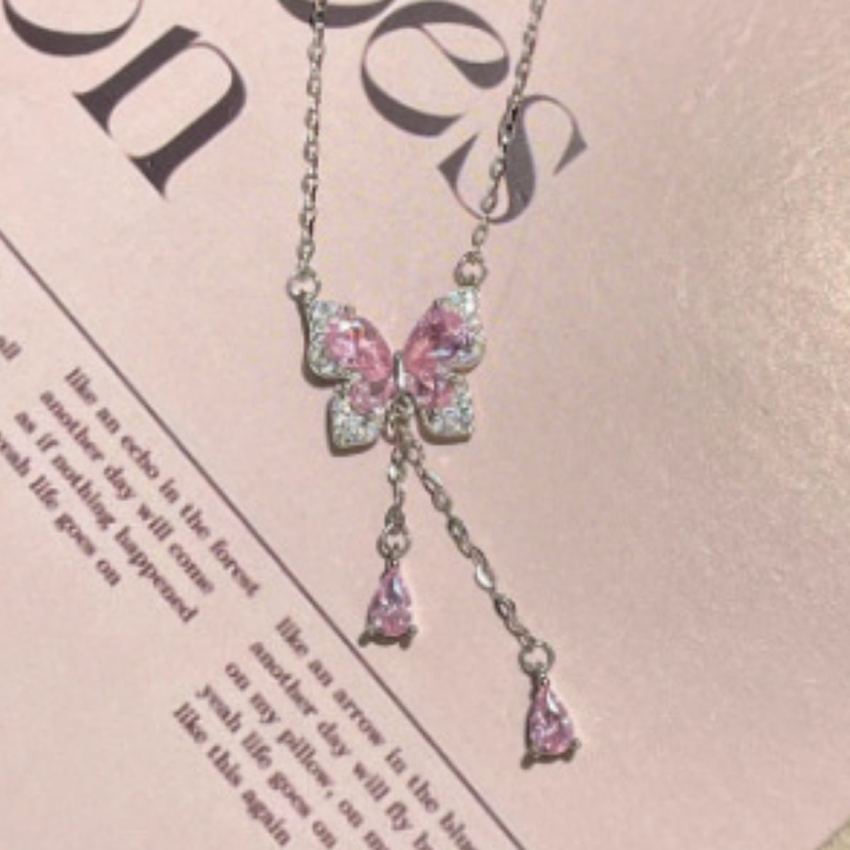 Close-up of pink-and-clear butterfly pendant necklace on printed paper