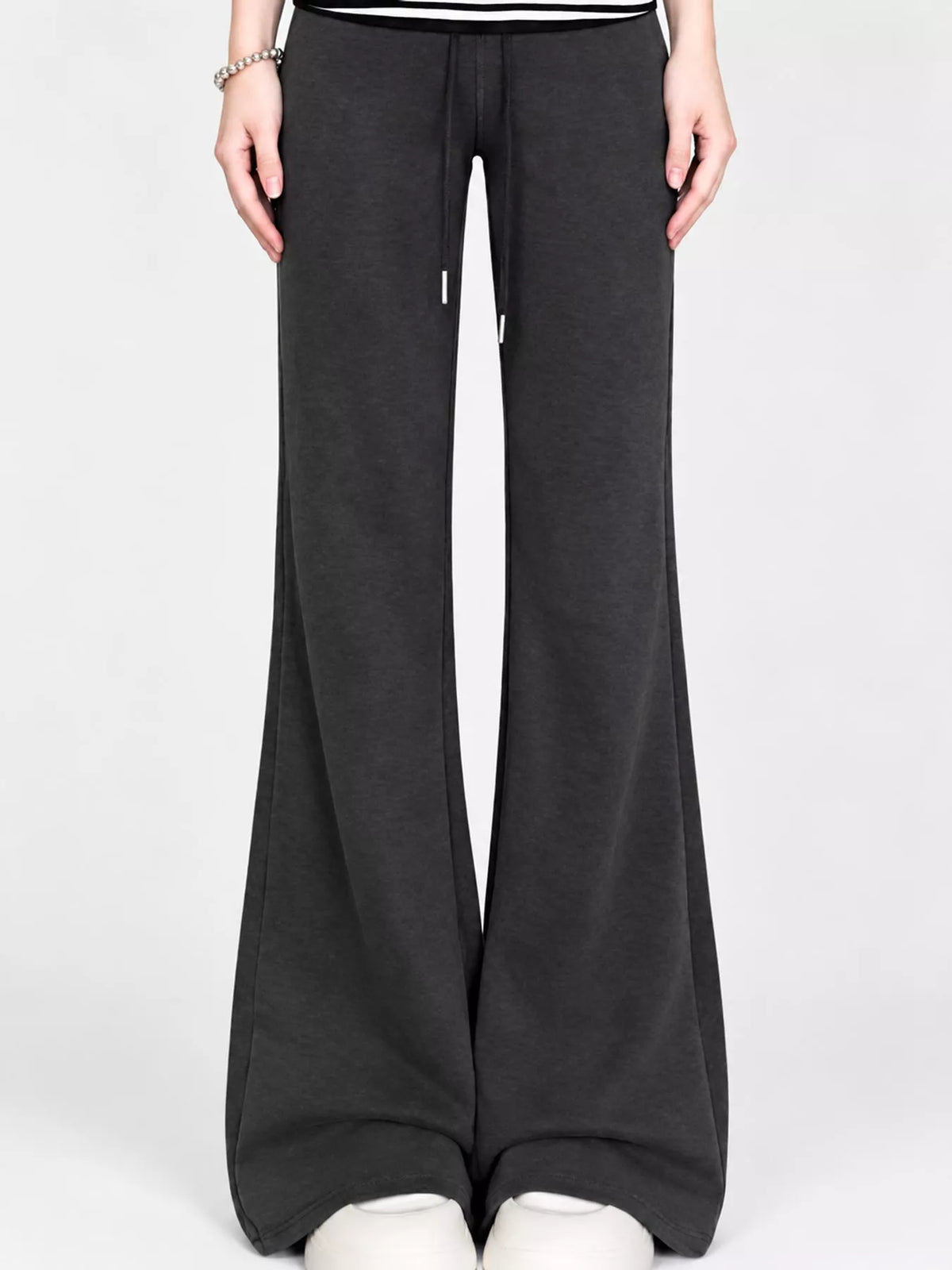 Black drawstring wide-leg flare pants worn with white shoes, front view