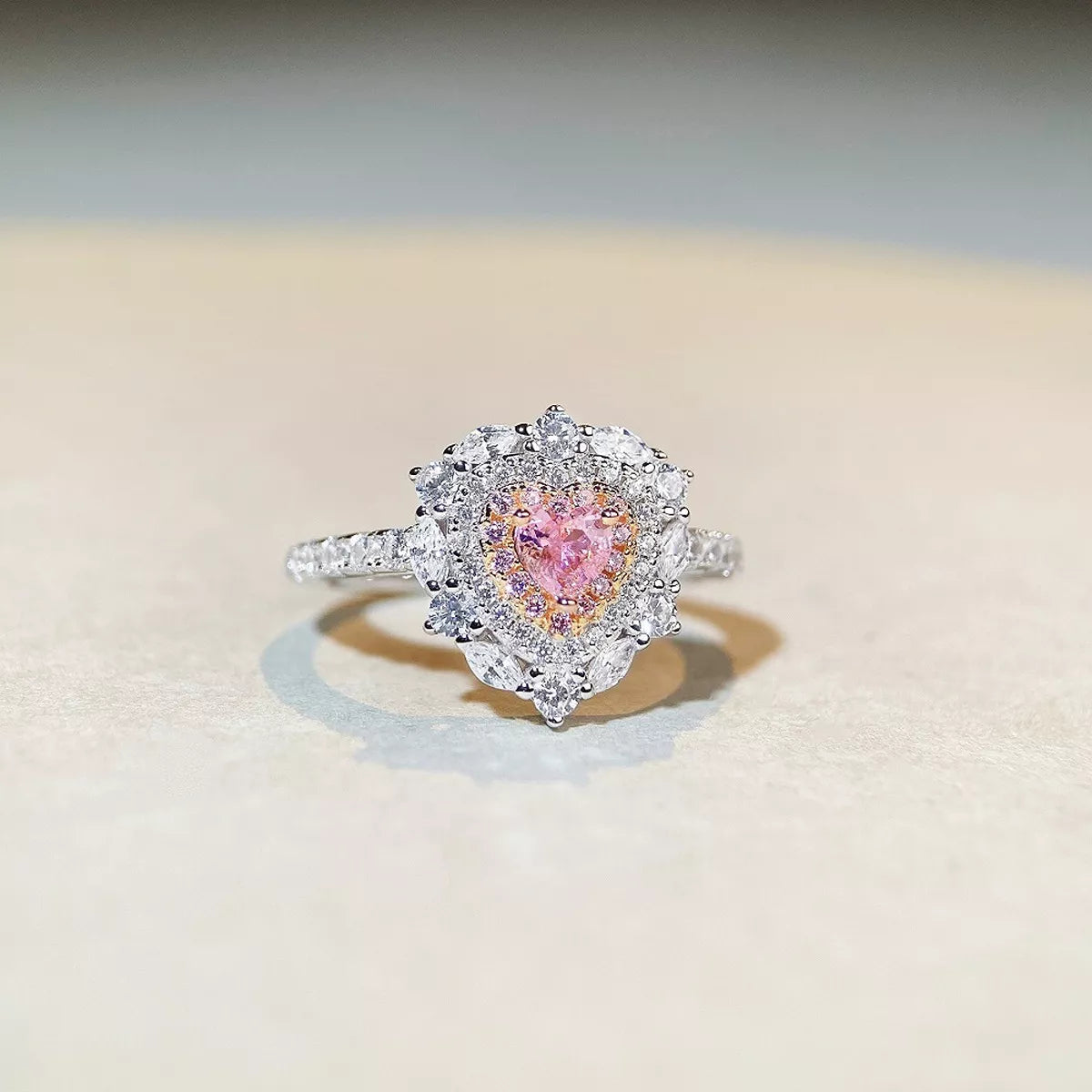 Silver-tone ring with a pink heart-shaped center stone framed by clear stones.