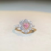 Silver-tone ring with a pink heart-shaped center stone framed by clear stones.