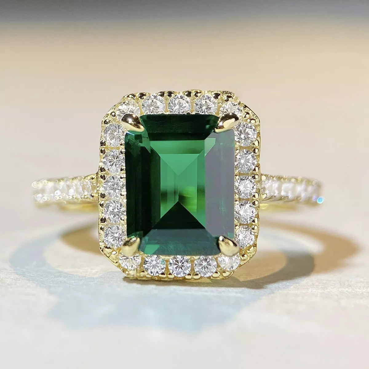 Front close-up of a rectangular green stone surrounded by clear accent stones.