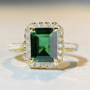 Front close-up of a rectangular green stone surrounded by clear accent stones.