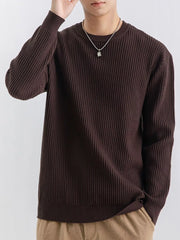 Model wearing a dark brown ribbed sweater with one hand raised beside the head