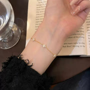 Silver clover bracelet on wrist beside a black cuff