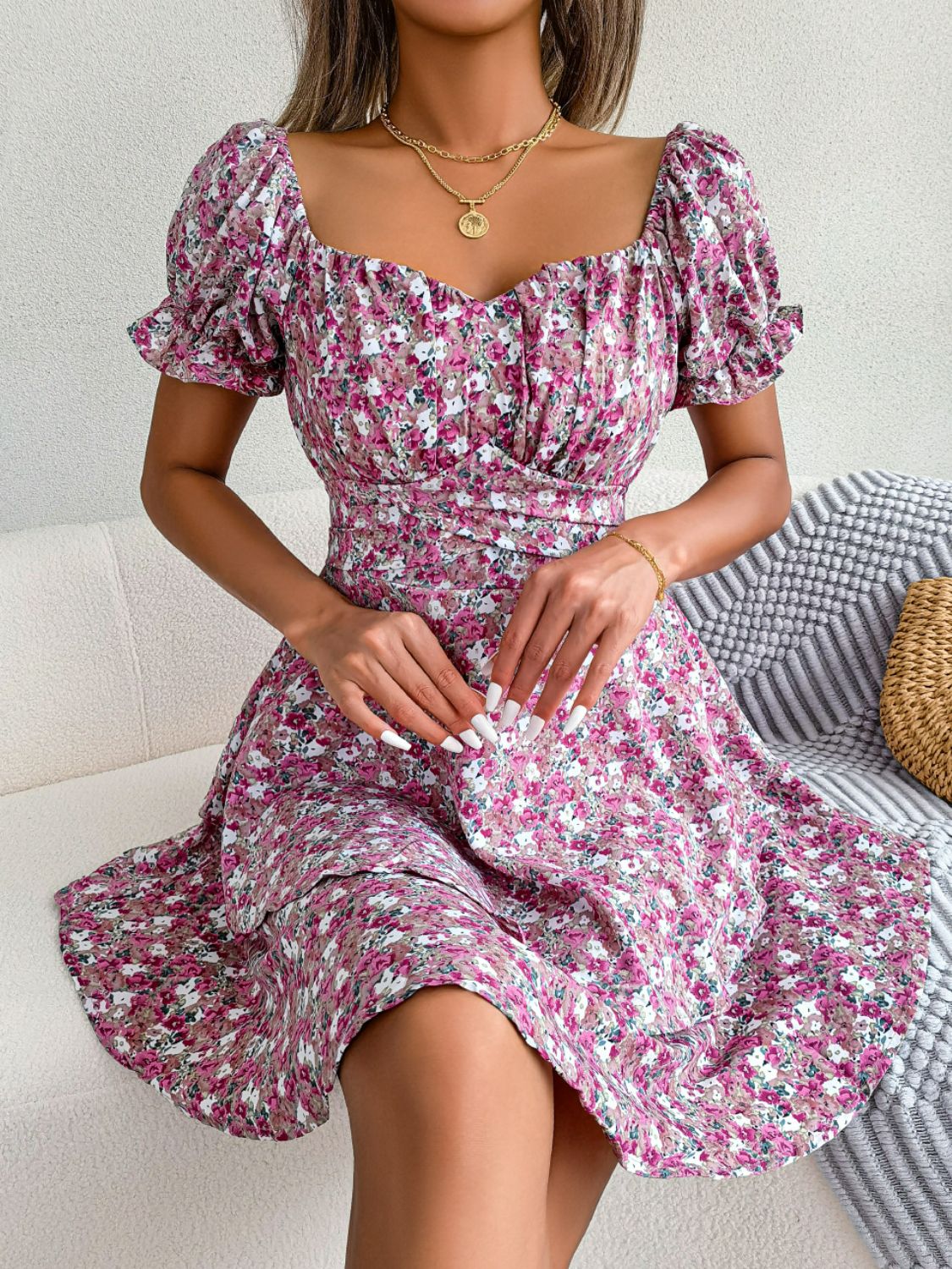 Model seated in magenta floral sweetheart-neck dress with flounce sleeves