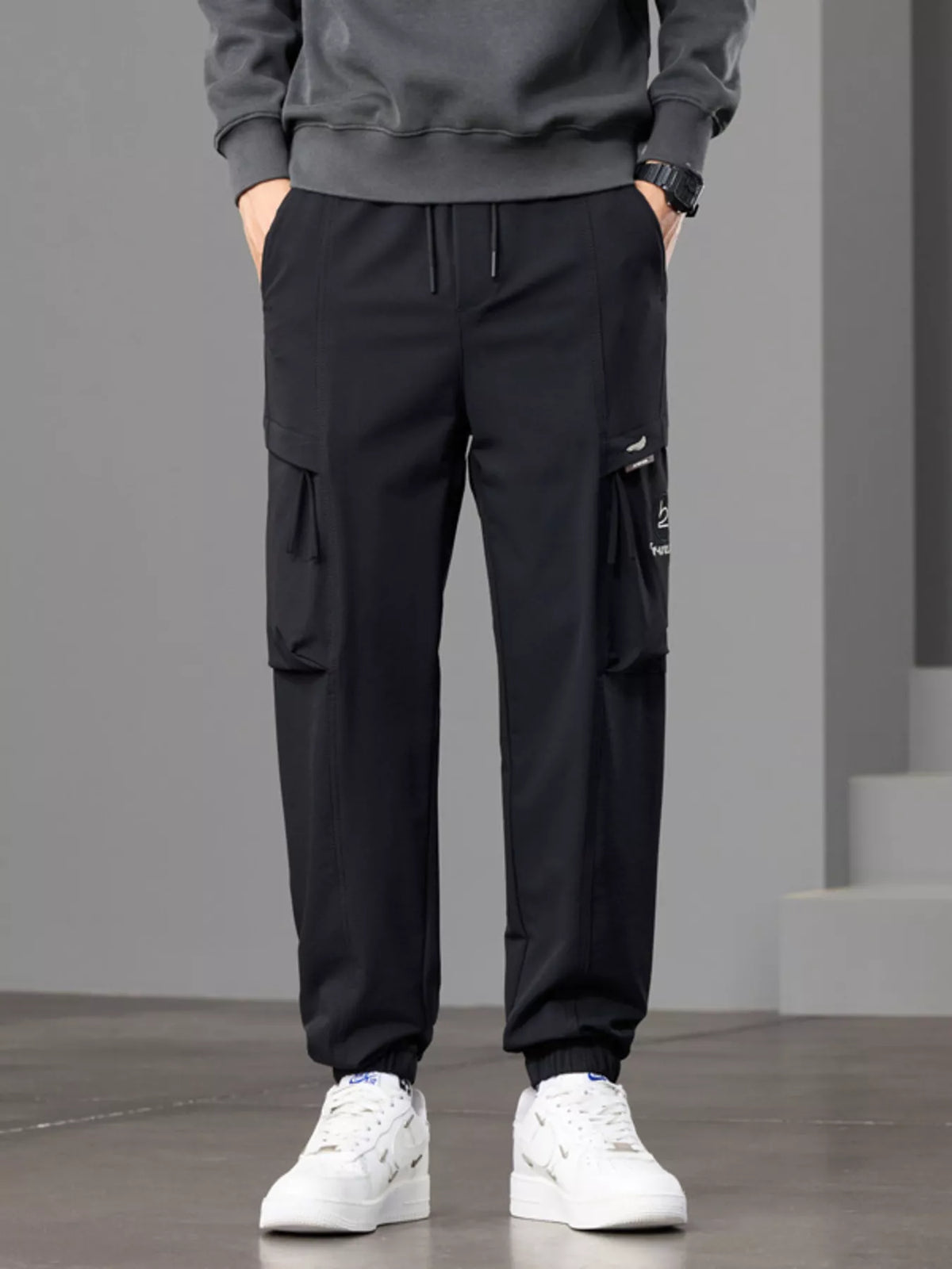 Front view of black cargo joggers with drawstring waist and flap thigh pockets.