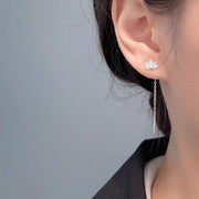 Close view of lotus stud and dangling chain earring worn on ear
