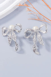Pair of silver-tone bow earrings with white bead studs and dangling accents