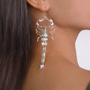 Silver-tone scorpion dangle earring worn on an ear, close view