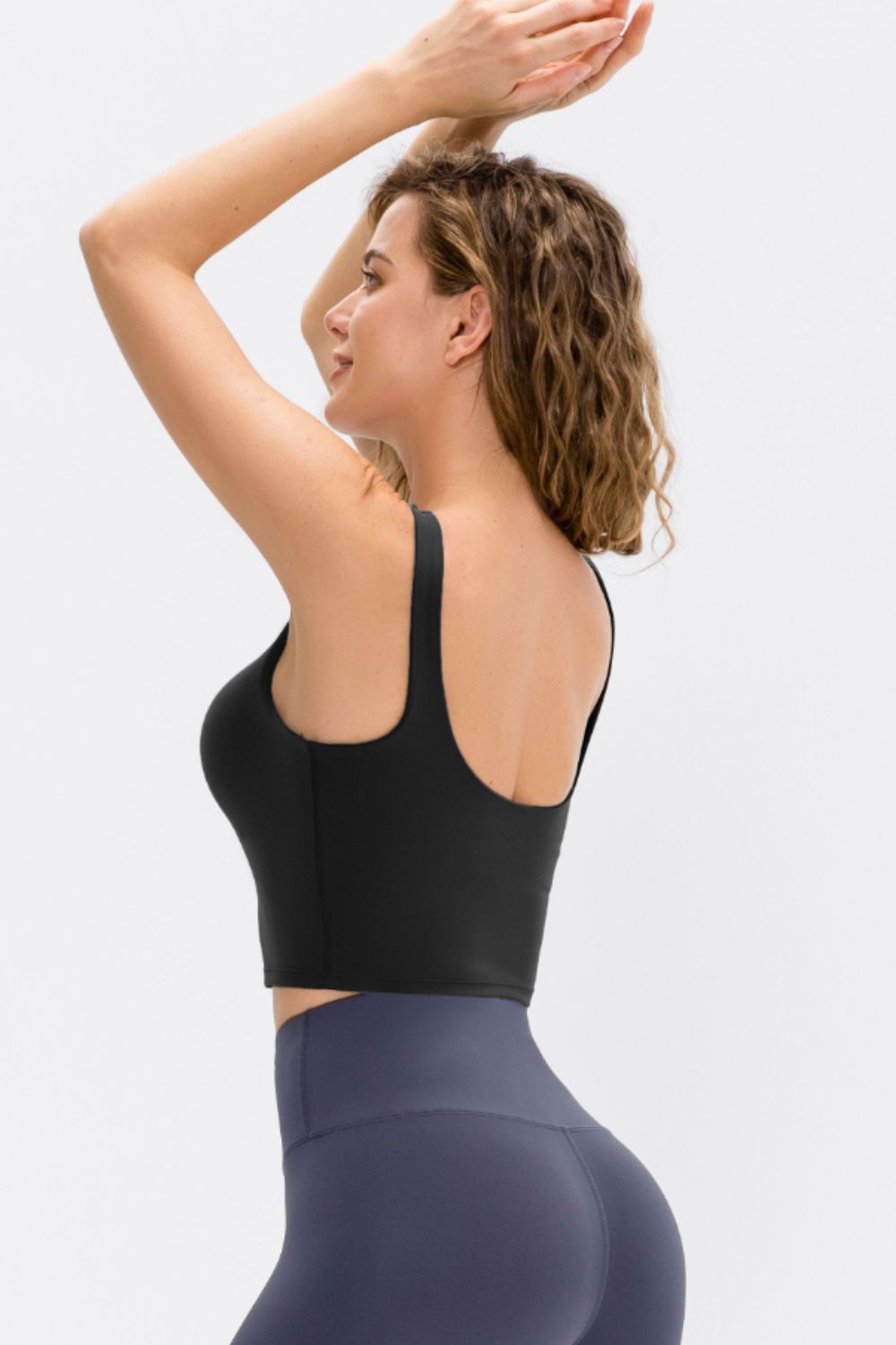 Side view of a model wearing a black scoop-neck cropped active tank