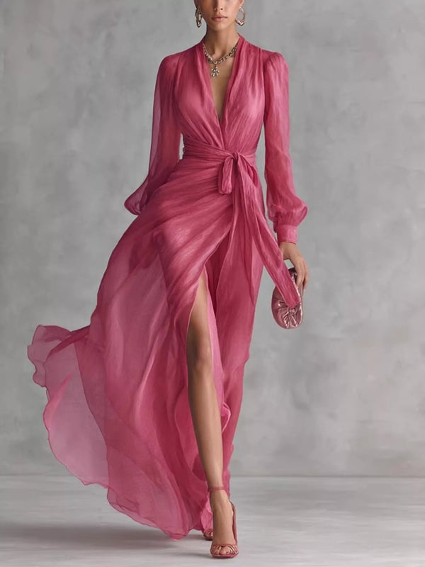 Pink long-sleeve wrap maxi dress with a tied waist and high slit, shown walking.