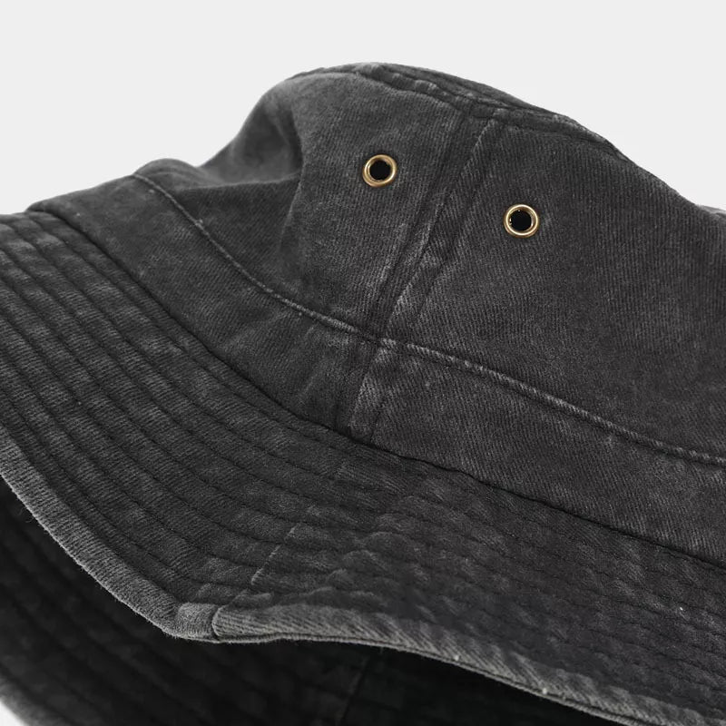 Close-up of the black bucket hat's stitched brim and metal eyelets