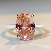 Front close-up of a faceted oval pink gemstone held by silver-tone prongs