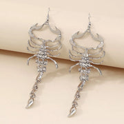 Pair of silver-tone scorpion earrings angled on a pale surface