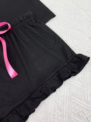 Detail of black lounge shorts showing the ruffled hem and pink bow