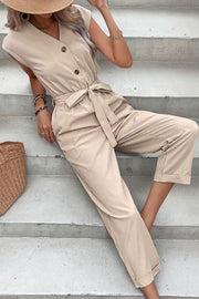 Seated pose in tan belted V-neck jumpsuit