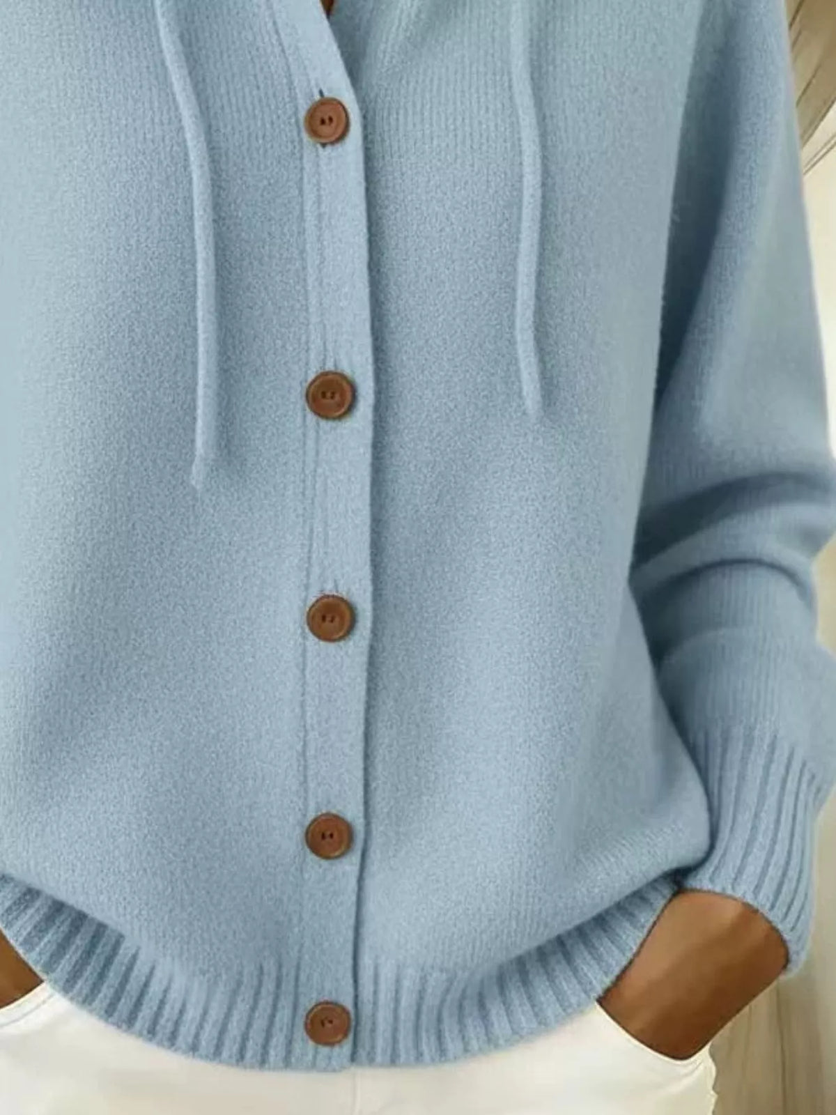 Detail of light blue cardigan ribbed hem and button-front closure
