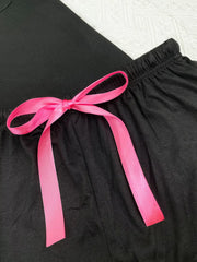 Close-up of black lounge shorts with a bright pink waist bow