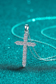 Close-up of sparkling cross pendant on teal background