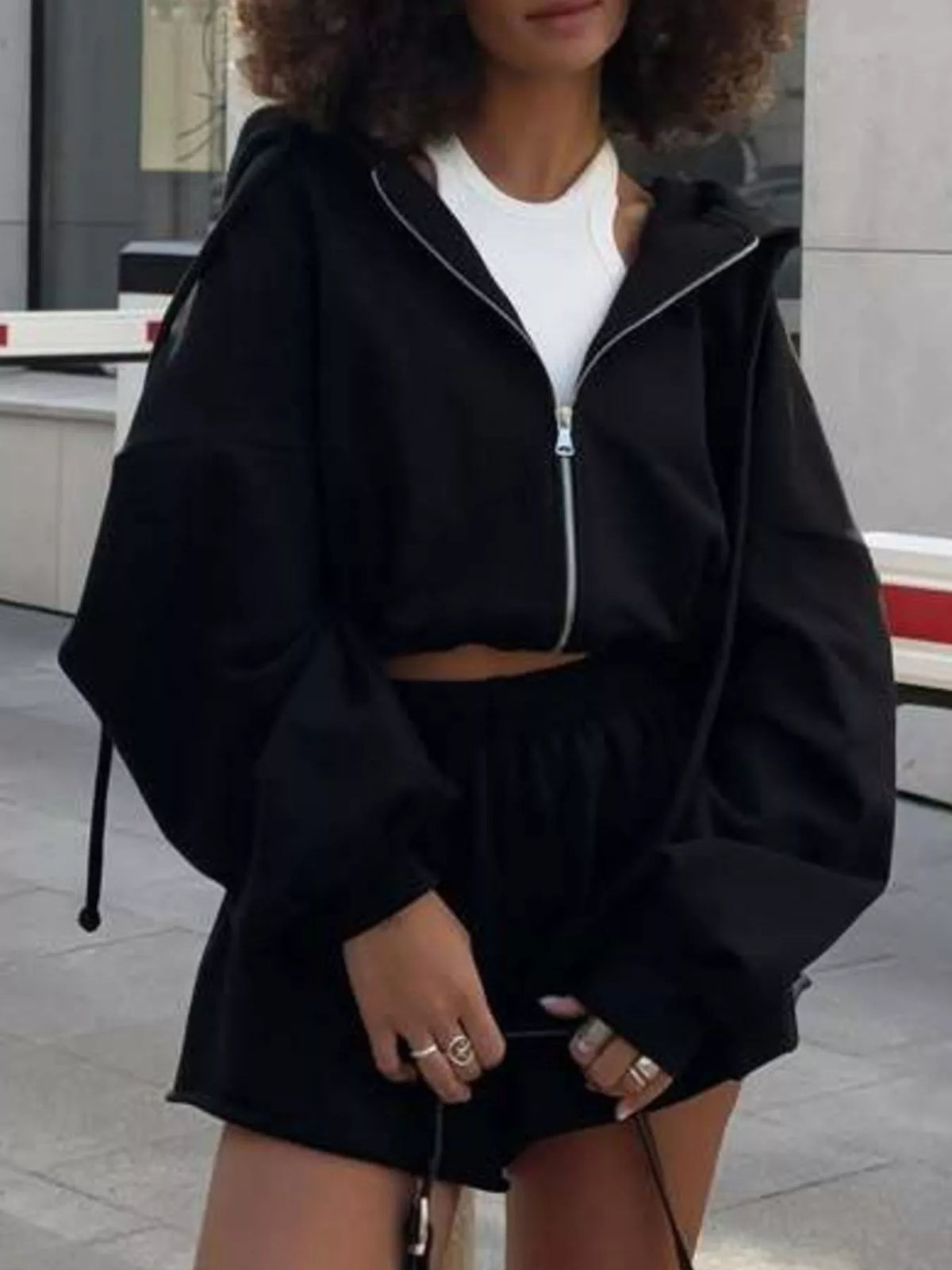 Model wearing black hoodie and shorts, standing front view