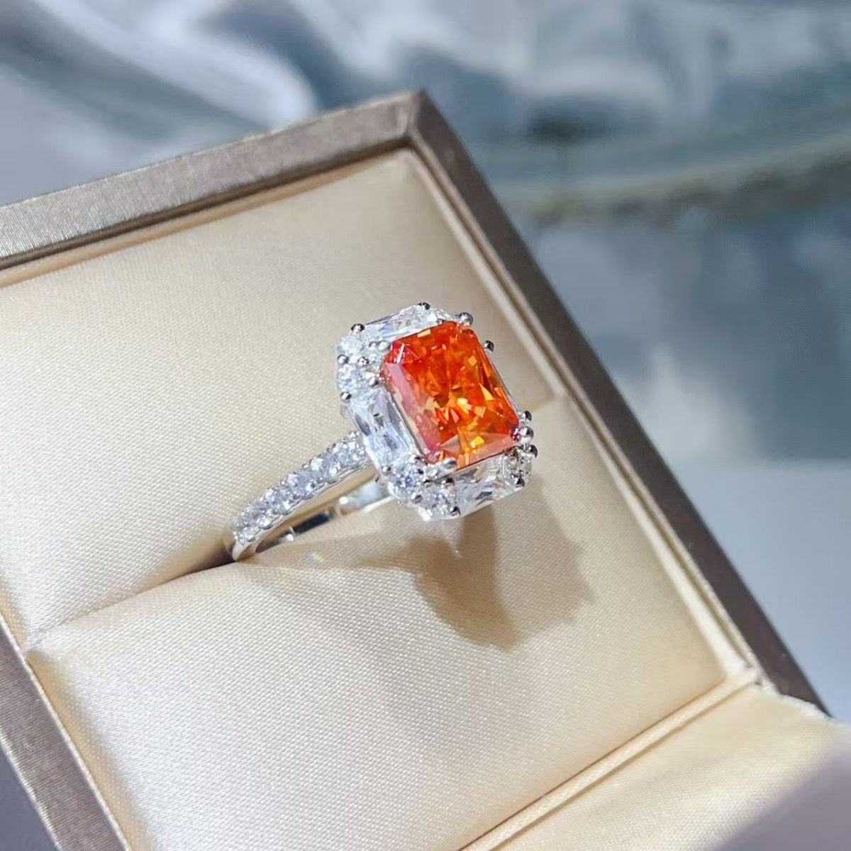 Angled view of orange center stone ring in a presentation box