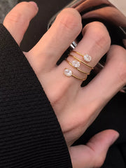 Three slim gold-tone rings with oval clear stones worn stacked on finger