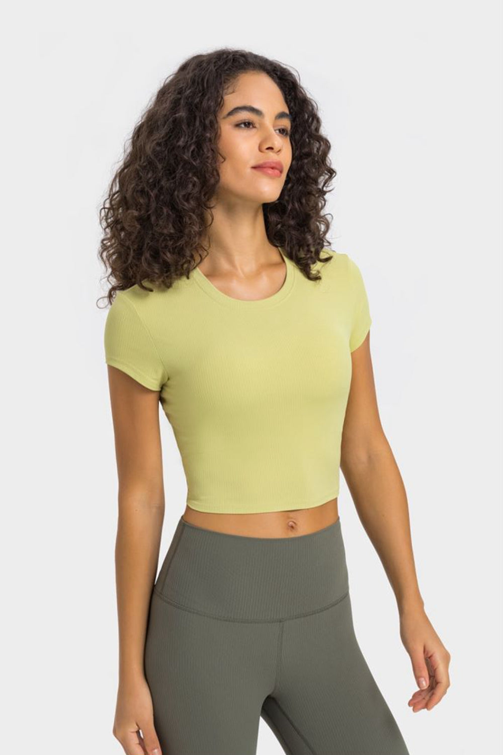 Model in pale yellow cropped T-shirt and gray leggings, three-quarter view