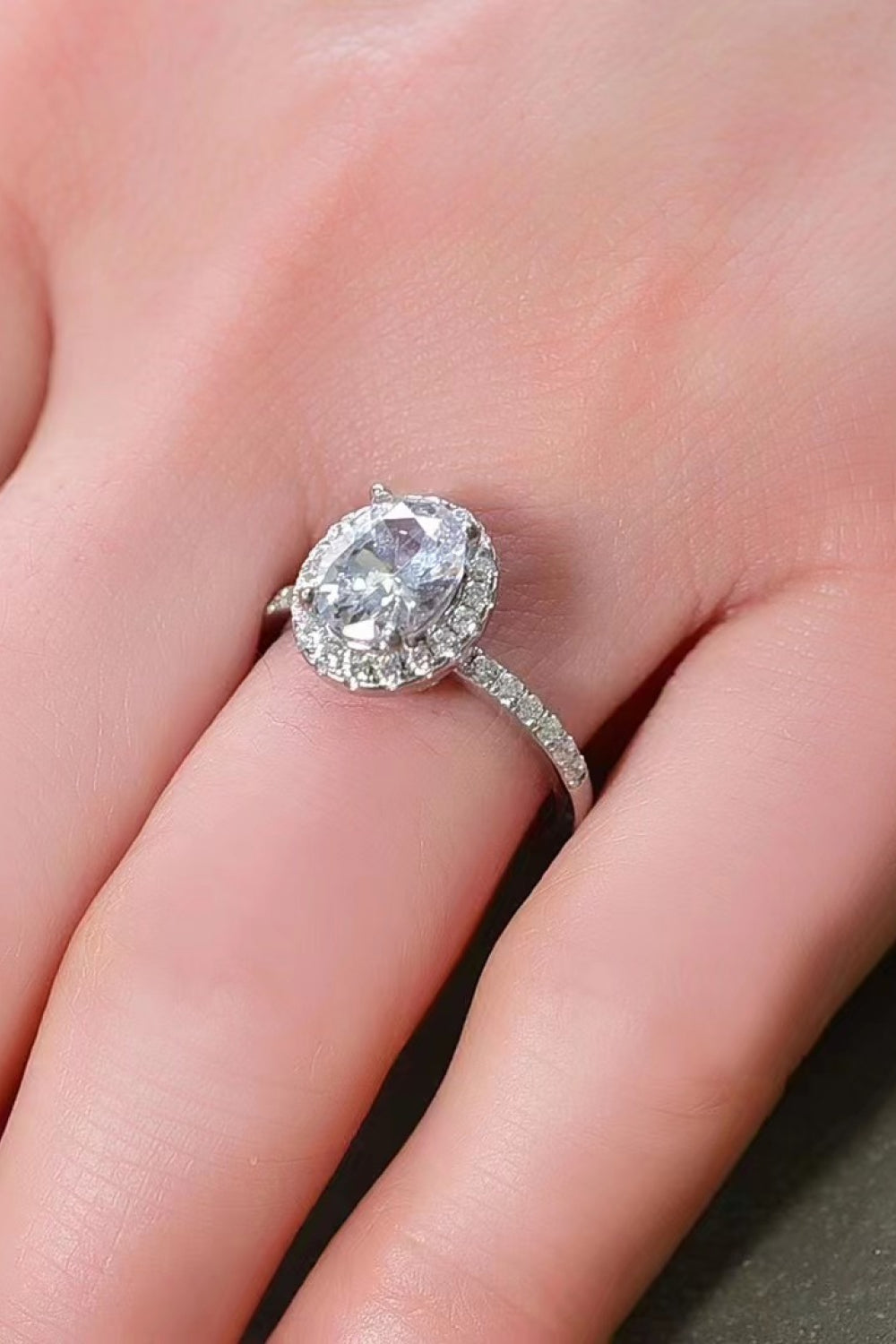 Platinum-plated oval moissanite ring on a dark display surface