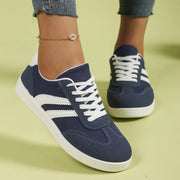 Navy flat shoes with white stripes worn, front angled view