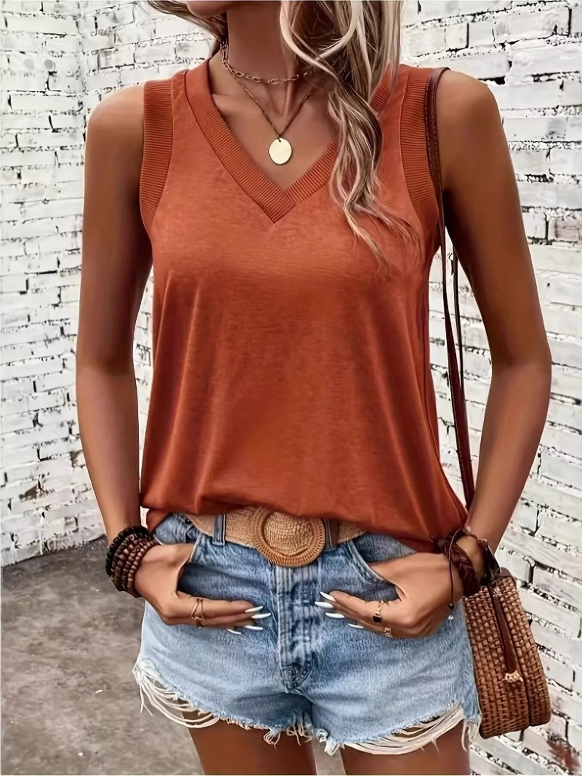 Model wearing rust-orange V-neck tank with denim shorts