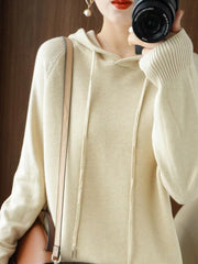 Cream drawstring hooded knit sweater, mirror-photo front view with a shoulder bag.
