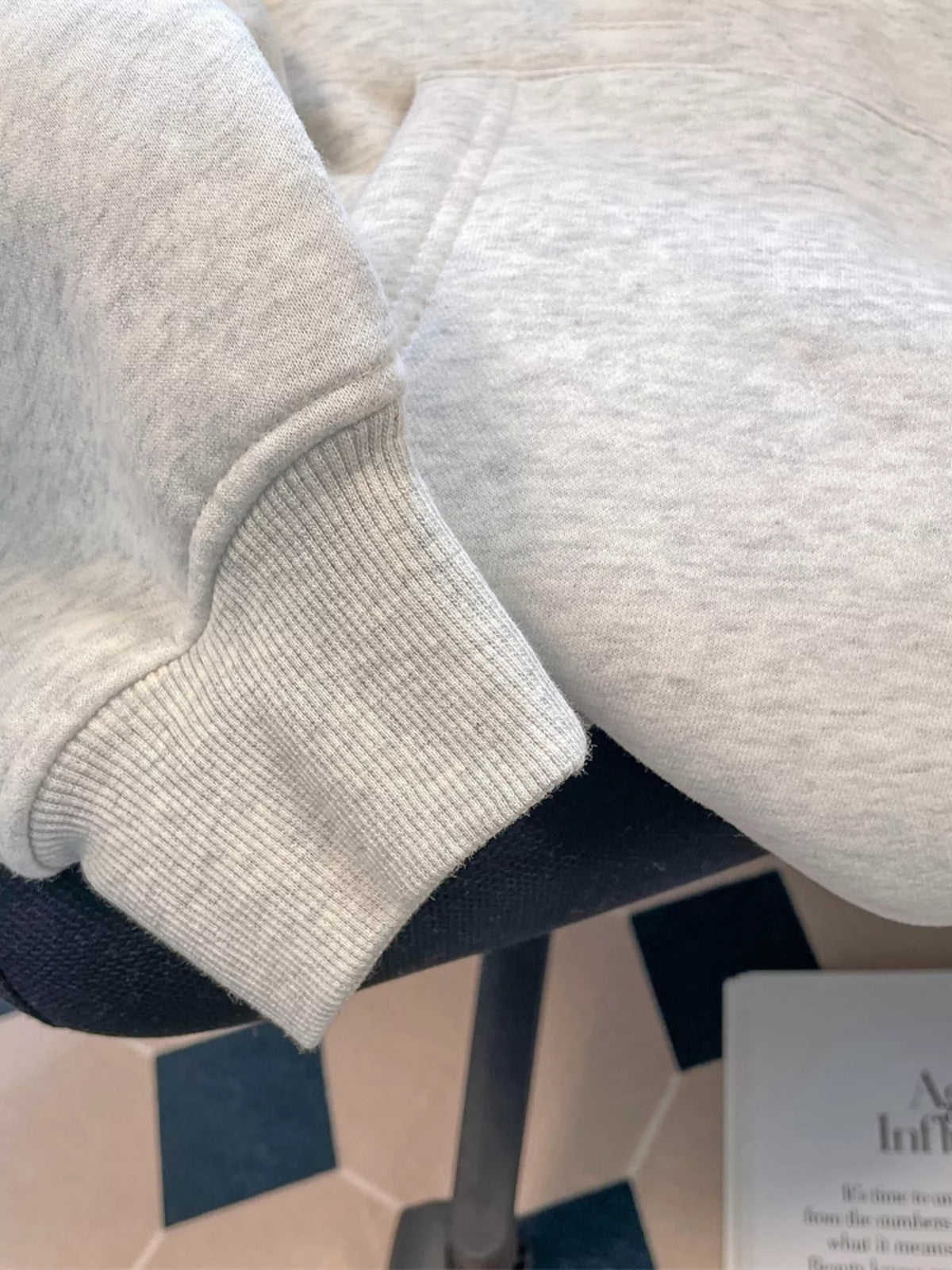 Close-up of light grey hoodie sleeve showing its ribbed cuff and heathered fabric